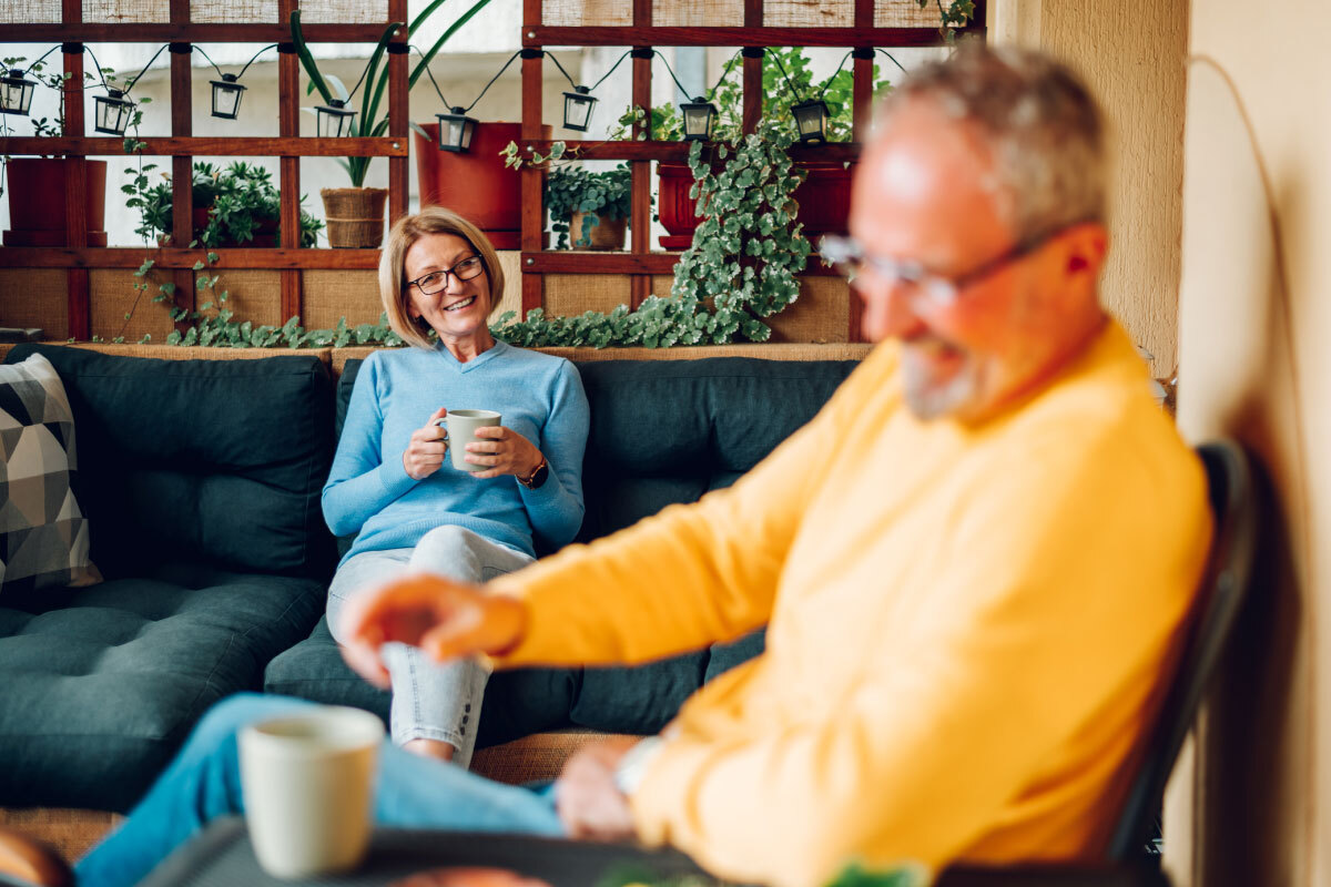 older-couple-drinking-coffee-on-balcony-of-house