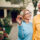 older-couple-holding-keys-standing-in-front-of-home